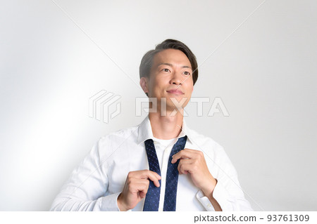 Businessman tying a tie while looking forward 93761309