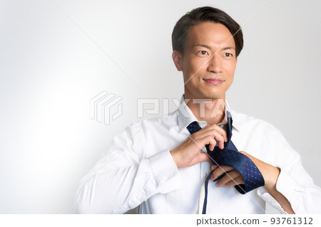Businessman tying a tie while looking forward 93761312