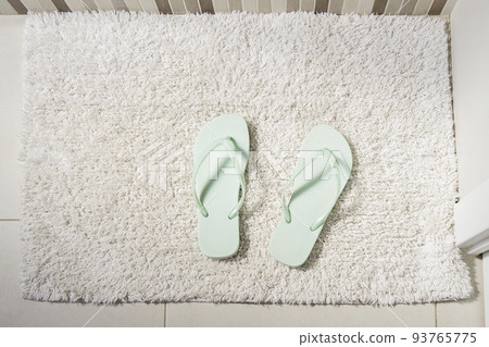 Pair peppermint flip-flops on white carpet in bathroom. Concept of cleanliness and personal care Pair peppermint flip-flops on white carpet in bathroom. Concept of cleanliness and personal care 93765775
