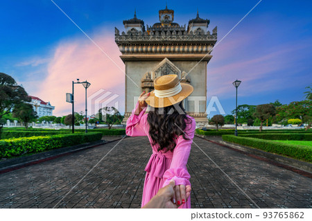 Women tourists holding man's hand and leading him to Patuxai in Vientiane, Laos. Women tourists holding man's hand and leading him to Patuxai in Vientiane, Laos. 93765862