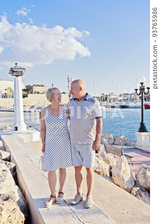 Middle-aged couple of baby boomers people posing for photograph opposite blue sea 93765986