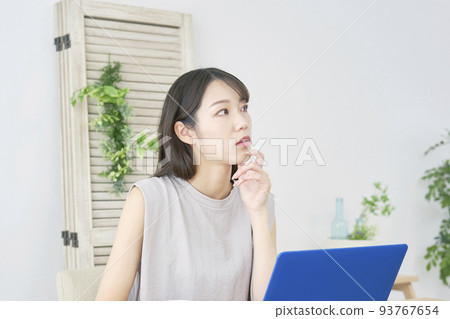 一個女人在客廳的筆記本電腦前思考 93767654