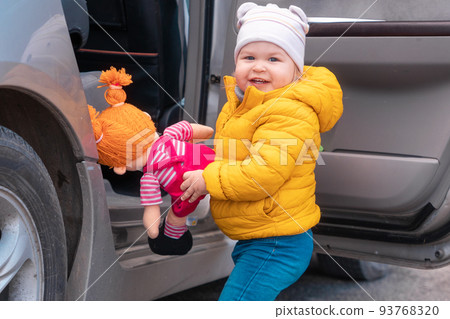 Happy little child assist to her doll sit in the car at children's backseat. The concept of safe trip and health insurance 93768320