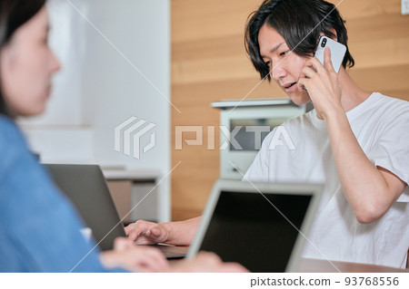 A young man calling on his smartphone during telework A young man calling on his smartphone during telework 93768556