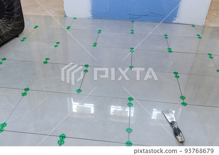 Currently under construction is a new house that has laying ceramic tiles in the bathroom 93768679