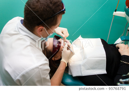 Dentist doctor does teeth whitening procedure for patient.. 93768791