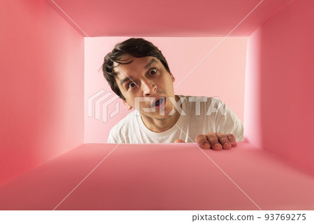 Young emotive man looking inside carton box with shocked expression Young emotive man looking inside carton box with shocked expression 93769275