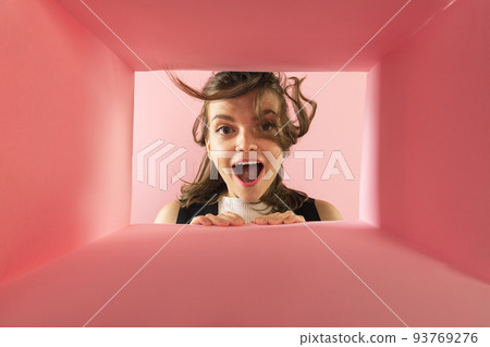 Cheerful and excited young girl looking inside carton box. Looking extremely happy Cheerful and excited young girl looking inside carton box. Looking extremely happy 93769276