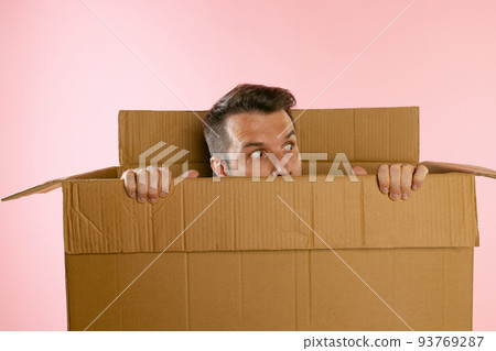 Portrait of funny man peeking out carton box isolated on pink background 93769287