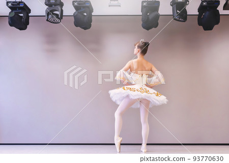 backview of the young caucasian ballet dancer practice ballet positions in professional tutu skirt of white swan. 93770630