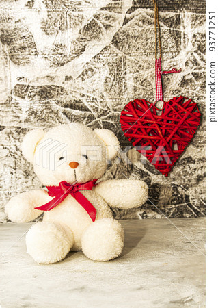 White Teddy bear with red heart on grey wall background 93771251