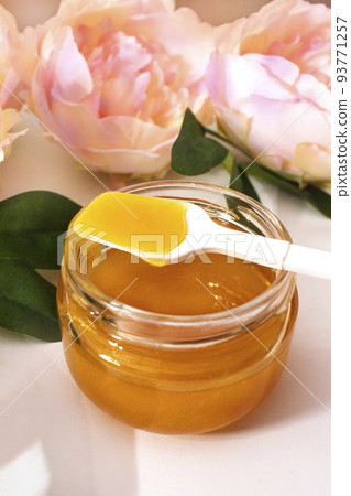 Liquid sugar paste for hair removal in a bowl with peony flower and feather on white background. Liquid sugar paste for hair removal in a bowl with peony flower and feather on white background. 93771257