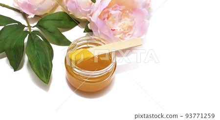 Liquid sugar paste for hair removal in a bowl with peony flower and feather on white background. 93771259