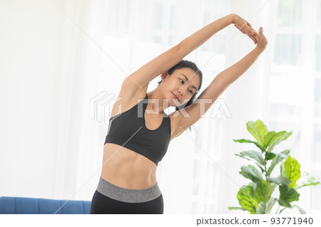 Calm of Asian woman in sportwear stretching muslce to warm up breathing and meditation with yoga at home. Healthy female stretching muscle comfortable and relax before exercise ready to workout 93771940