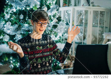 Millenial, gen Z young man having online video chat on laptop and talking to friends or family on virtual call. Christmas online celebration. Happy New Year online party. Selective focus. 93772282
