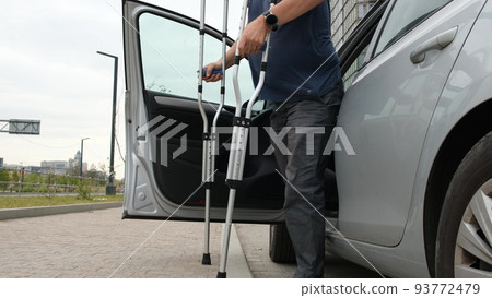 Man with leg injury comes out of car wash using crutches 93772479