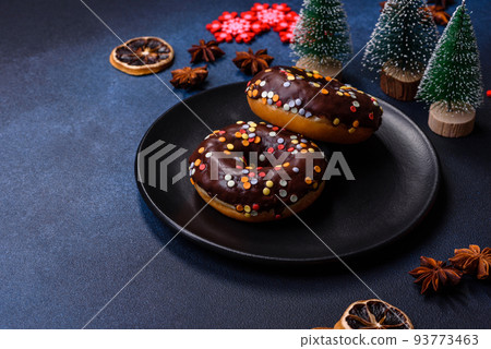 Pastries concept. Donuts with chocolate glaze with sprinkles, on a dark concrete table 93773463