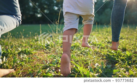 children run in the park. bare feet close-up group of children running on green grass in summer. happy family kid dream concept. baby running barefoot in the park lifestyle 93773682