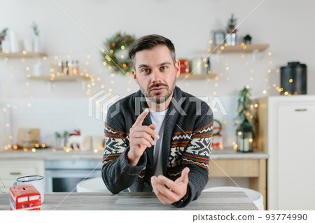 The man himself at home looks at the camera and communicates via video link, view from the webcam, greets friends and colleagues with Christmas and New Year holidays 93774990