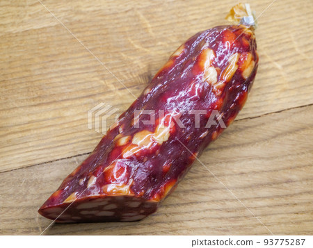 Half of an appetizing sausage on a wooden background, close-up shot. Food on a cutting board. Smoked sausage on a rustic table. Half of an appetizing sausage on a wooden background, close-up shot. Food on a cutting board. Smoked sausage on a rustic table. 93775287