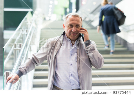 Middle aged man with phone going down stairs in mall 93775444