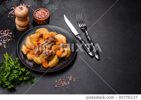 Beef meat and vegetables stew on a black plate with roasted potatoes Beef meat and vegetables stew on a black plate with roasted potatoes 93776137