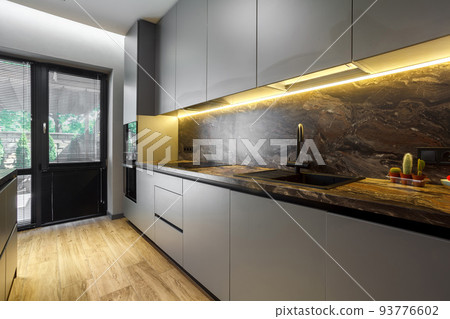 Modern luxury apartment with a free layout in a loft style in gray and dark colors. Stylish kitchen area with an island, marble countertop Modern luxury apartment with a free layout in a loft style in gray and dark colors. Stylish kitchen area with an island, marble countertop 93776602