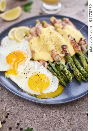 Healthy tasty breakfast - Asparagus wrapped with bacon and fried eggs on a plate 93778770