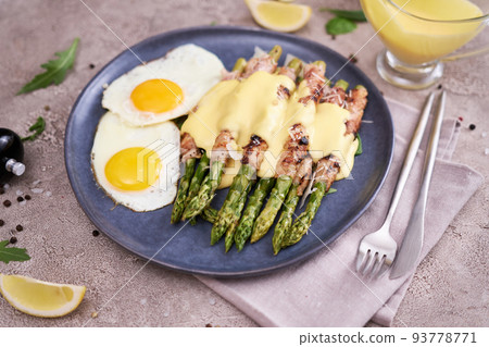 Healthy tasty breakfast - Asparagus wrapped with bacon and fried eggs on a plate Healthy tasty breakfast - Asparagus wrapped with bacon and fried eggs on a plate 93778771