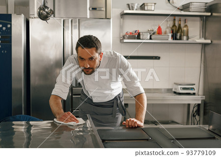 Young handsome male chef cleaning his workplace on kitchen in restaurant Young handsome male chef cleaning his workplace on kitchen in restaurant 93779109