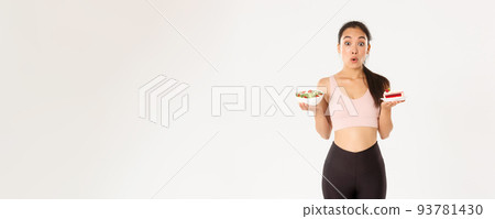 Active lifestyle, fitness and wellbeing concept. Portrait of indecisive and tempting cute asian girl trying resist temptation as holding delicious cake, being on diet, looking at healthy salad Active lifestyle, fitness and wellbeing concept. Portrait of indecisive and tempting cute asian girl trying resist temptation as holding delicious cake, being on diet, looking at healthy salad 93781430