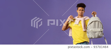Education, university and trends concept. Portrait of gloomy disappointed young male student complaining on ugly new backpack, show thumbs-down and grimacing displeased, purple background Education, university and trends concept. Portrait of gloomy disappointed young male student complaining on ugly new backpack, show thumbs-down and grimacing displeased, purple background 93781464