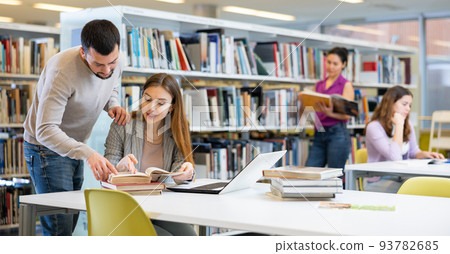 Male and female students preparing for exam together in library 93782685