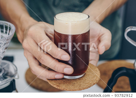Barista holding and serving a drinking glass of cold brew dip coffee. Barista holding and serving a drinking glass of cold brew dip coffee. 93782912