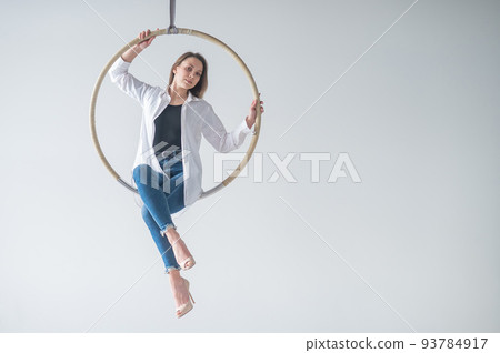Caucasian woman gymnast on an aerial hoop takes a selfie on a smartphone. Caucasian woman gymnast on an aerial hoop takes a selfie on a smartphone. 93784917