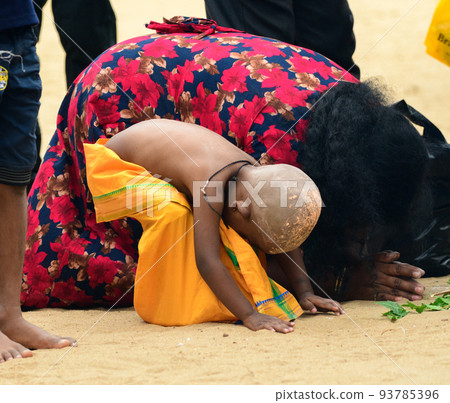 Hindu devotees in Katagama Dewalaya, Mother, and her son kneel down on the sand and worships the God of Kataragama. 93785396