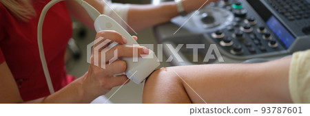 Doctor making ultrasound of patient elbow joint in clinic closeup 93787601