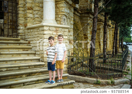 Two little boys with modern haircuts near the stairs in colorful T-shirts and single tone pants. Concept of modern little boys 93788554