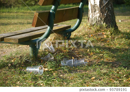 Pile of disposable cups alongside a wooden bench 93789191