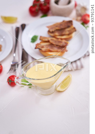 Classic Hollandaise sauce of butter and egg yolks served in a gravy boat 93791141