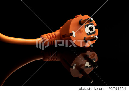 Orange electric plug on the black background. 93791334