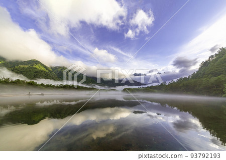 Kamikochi and Taisho Pond in the early morning. A misty mountain and blue sky reflected on the surface of the lake. 93792193
