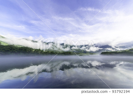 Kamikochi and Taisho Pond in the early morning. A misty mountain and blue sky reflected on the surface of the lake. 93792194