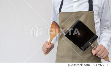 A man wearing an apron | Image of a man doing housework and cooking 93792205