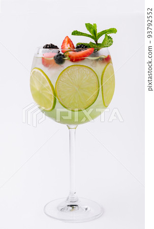 Drink with berries, with lime slices and mint in a wine glass 93792552