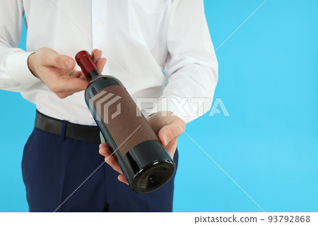 Waiter man holds bottle of wine on blue background 93792868