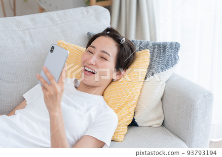 看智能手機的一位微笑的中年婦女 93793194