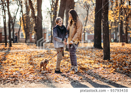 Autumn walks with the family. Happy family mother and teen boy son having fun with cocker spaniel puppy in autumn park Autumn walks with the family. Happy family mother and teen boy son having fun with cocker spaniel puppy in autumn park 93793438