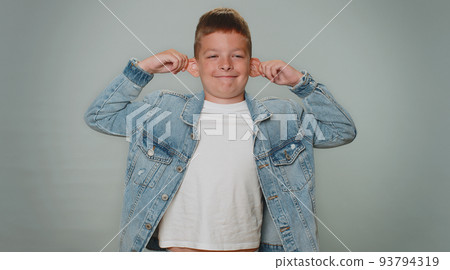 Funny toddler boy making playful silly facial expressions, grimacing, fooling around showing tongue 93794319
