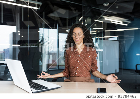 Young beautiful Hispanic web developer working inside office building, woman resting meditating at workplace with eyes closed, female worker using laptop to write code. Young beautiful Hispanic web developer working inside office building, woman resting meditating at workplace with eyes closed, female worker using laptop to write code. 93794462